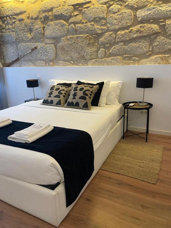 een slaapkamer met een wit bed en een stenen muur bij Casa da Ana in Porto