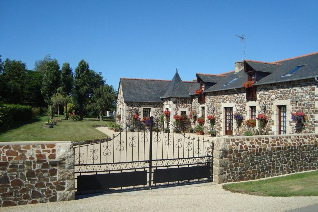 a fence in front of a stone house with flowers at La vieux ville in Trégomeur