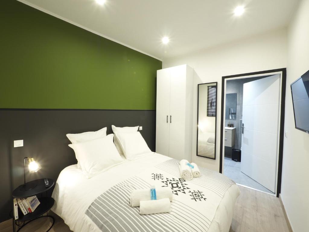 a bedroom with a large white bed with a green wall at 06R - Beau T2 moderne - Vieux Nice in Nice