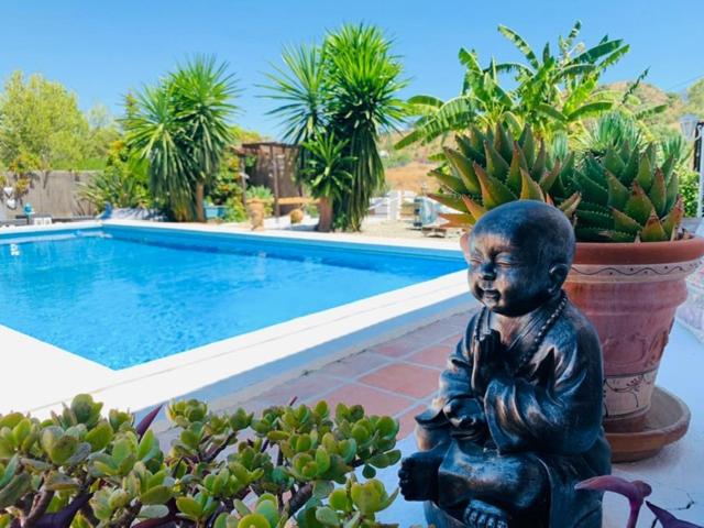 una estatua de un niño sentado junto a una piscina en Finca del Gecko en Alhaurín el Grande