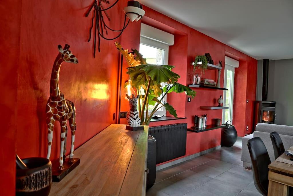 twee giraffen beelden op een houten tafel in een rode kamer bij Gîte des Zèbres Aventuriers... in L'Etang-Bertrand