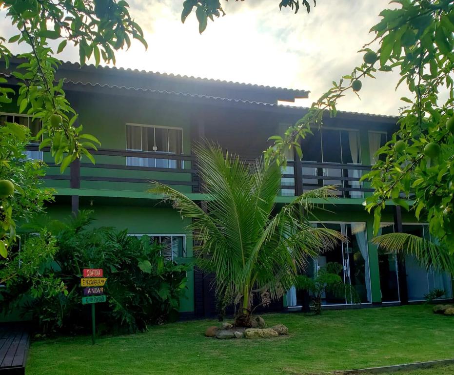 a building with a palm tree in front of it at Morada Flores de Alaíde - Pinheira in Pinheiro