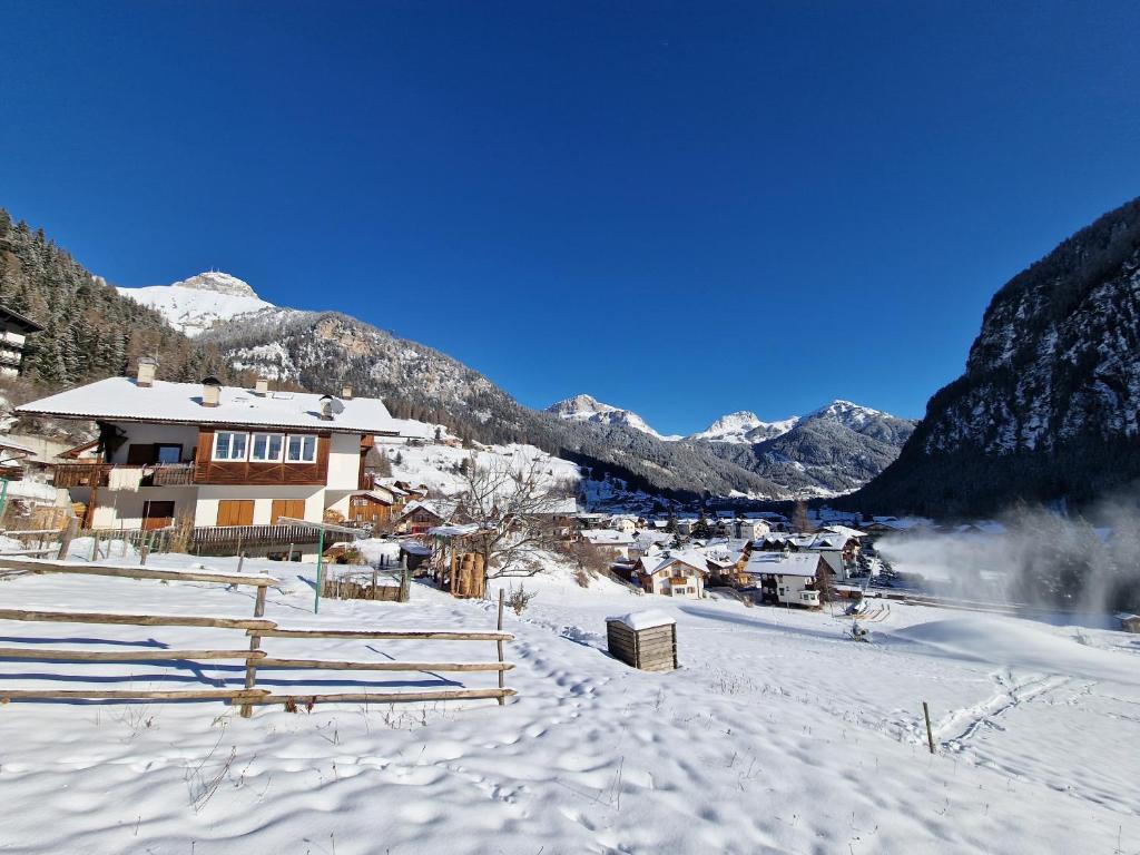 a village in the snow with mountains in the background at Cèsa Cherpei - Dog Friendly in Campitello di Fassa