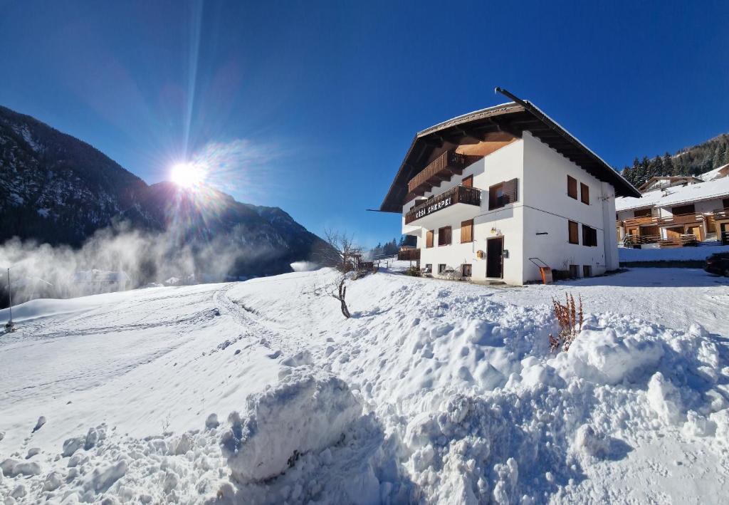 a building on a snow covered mountain with the sun in the sky at Cèsa Cherpei - Pet Friendly in Campitello di Fassa