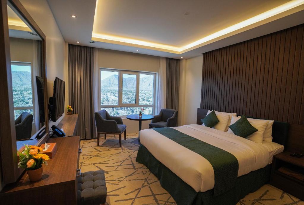 ein Hotelzimmer mit einem Bett, einem Schreibtisch und Stühlen in der Unterkunft Green View Hotel, Jabal Akhdar in Jabal Al Akhdar