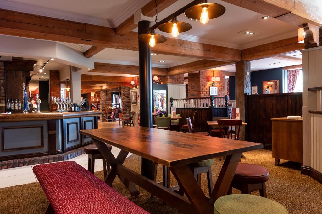 a restaurant with a wooden table and a bar at Toby Carvery Strathclyde, M74 J6 by Innkeeper's Collection in Motherwell