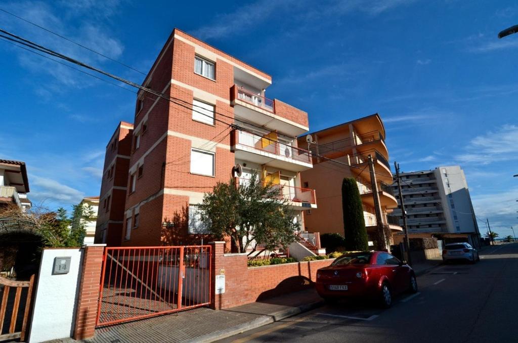 um edifício de tijolos com um carro vermelho estacionado em frente em BONAMAR Bxs 3 em L'Estartit