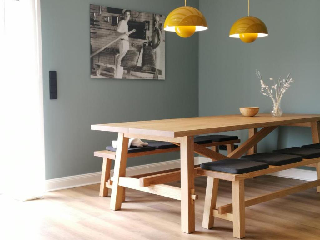 une salle à manger avec une table et des bancs en bois dans l'établissement Ferienhaus Urban Fewo Alte Backstube 2-4 Personen WLAN gegenüber vom Strand, à Niendorf