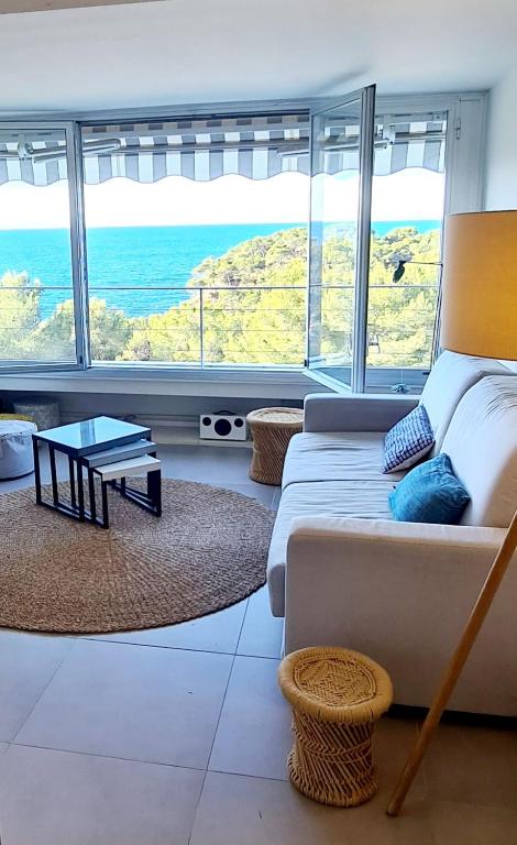 un salon avec un canapé et une grande fenêtre dans l'établissement SUPERBE APPARTEMENT VUE MER - PLAGE, PISCINE et TENNIS PRIVE, à Bandol
