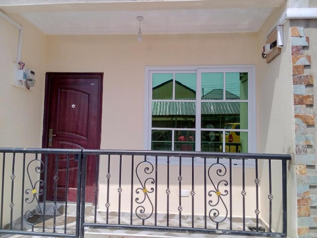 a house with a door and a balcony at BH Apartment in Kasoa