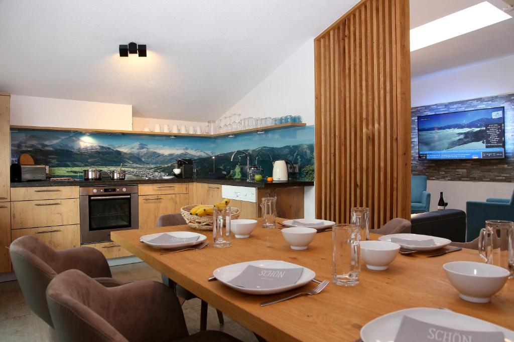uma sala de jantar com uma mesa de madeira com cadeiras em Alm Appartements ZellamSee em Zell am See