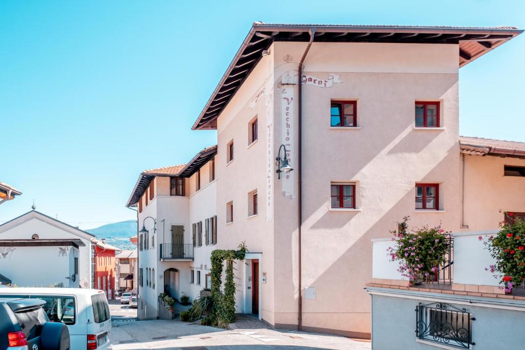 a pink building in a street with cars parked at Garnì Vecchio Comune in Flavon