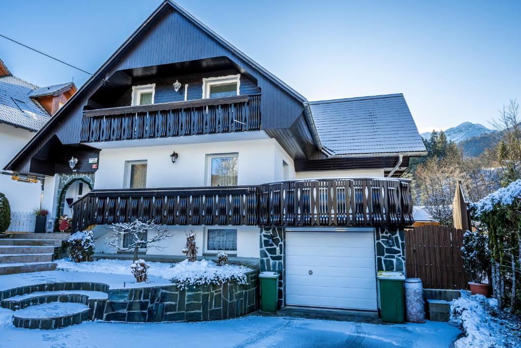 a white house with a black roof in the snow at Apartments Sara in Bohinj