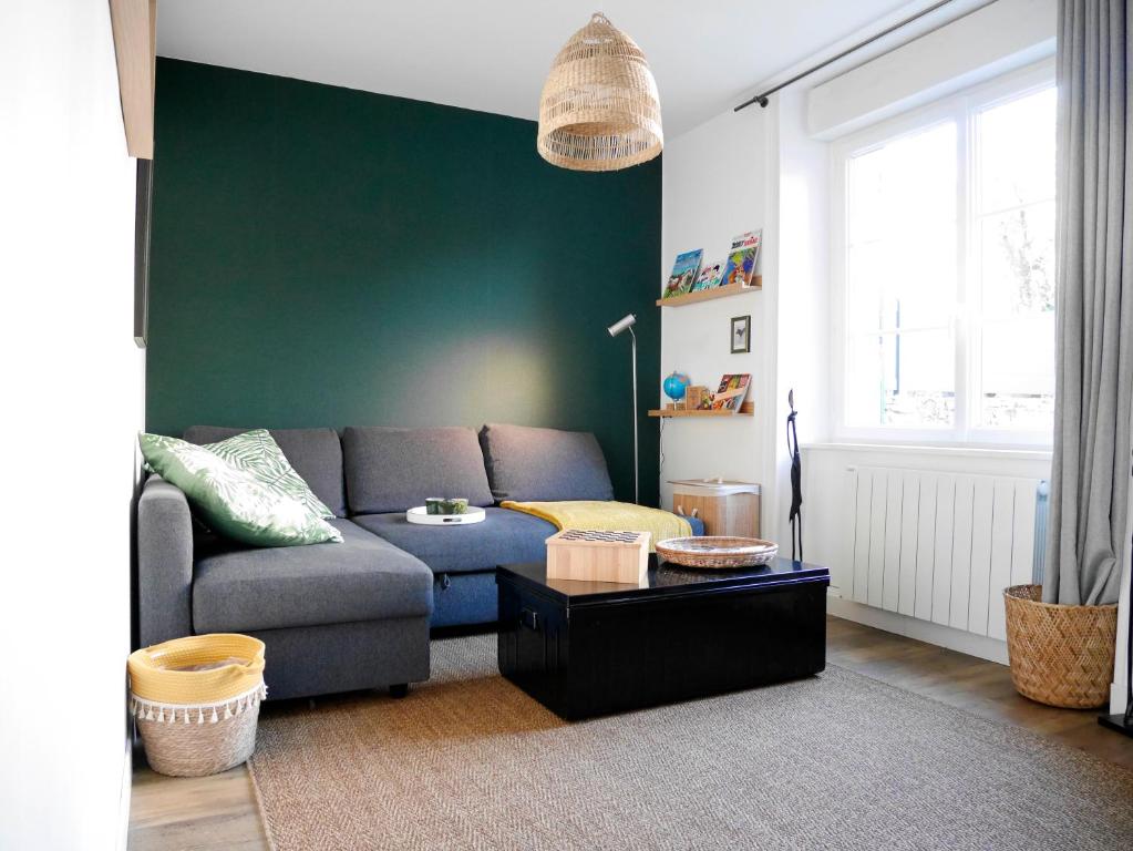 a living room with a couch and a green wall at CLINT HOUSE - Appartement "Jardin de granit rose" in Perros-Guirec