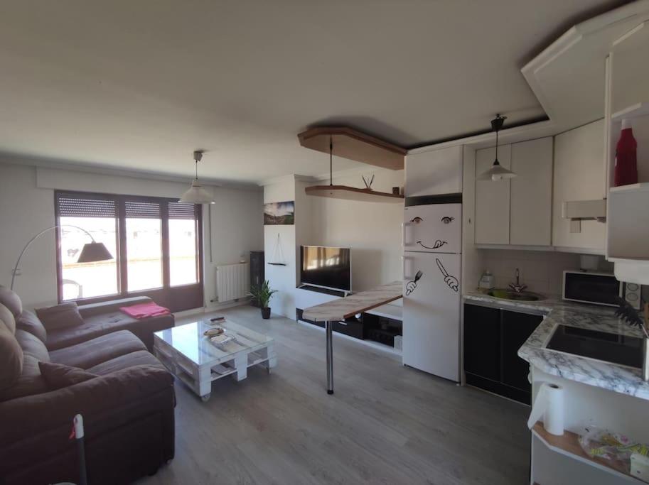 een keuken en een woonkamer met een bank en een tafel bij ATICO Romo in Santa Marta de Tormes