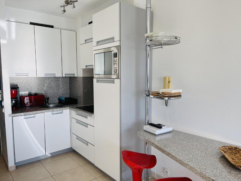 a kitchen with white cabinets and a red chair at Floriana in Cannes