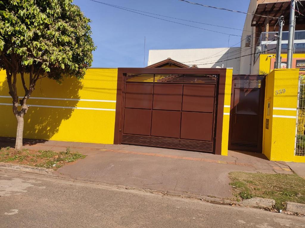 un mur jaune avec une porte de garage marron dans une rue dans l'établissement Casa mobiliada, à Campo Grande