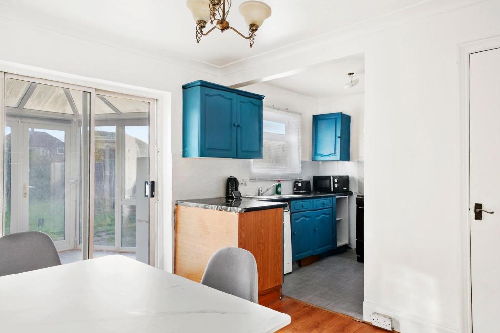 a kitchen with blue cabinets and a table at 3bed Cozy House Parking Wifi in Welling