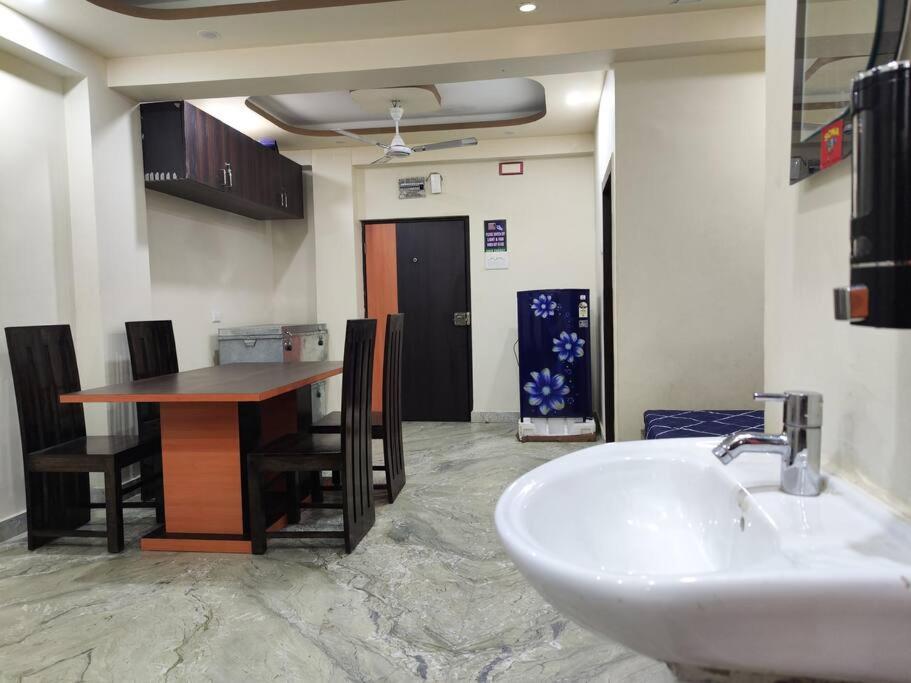 uma casa de banho com um lavatório e uma mesa com cadeiras em Lavish 2BHK, 10 mins from AMRI Hospital Dhakuria em Calcutá