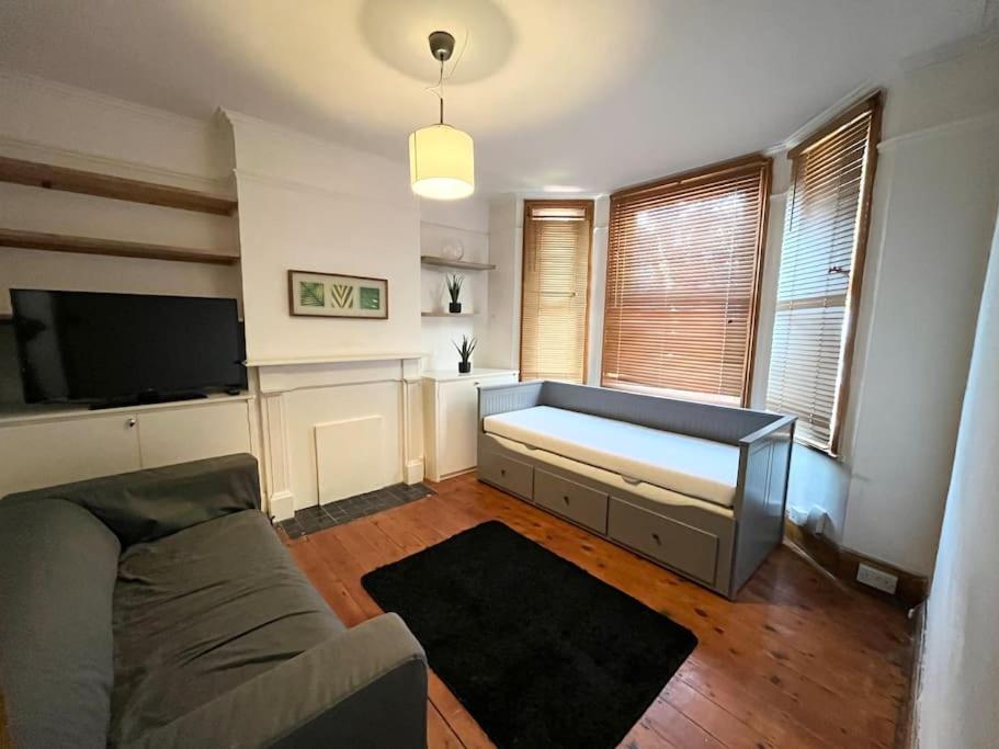 sala de estar con sofá y TV de pantalla plana en Spacious flat with patio garden en Raynes Park