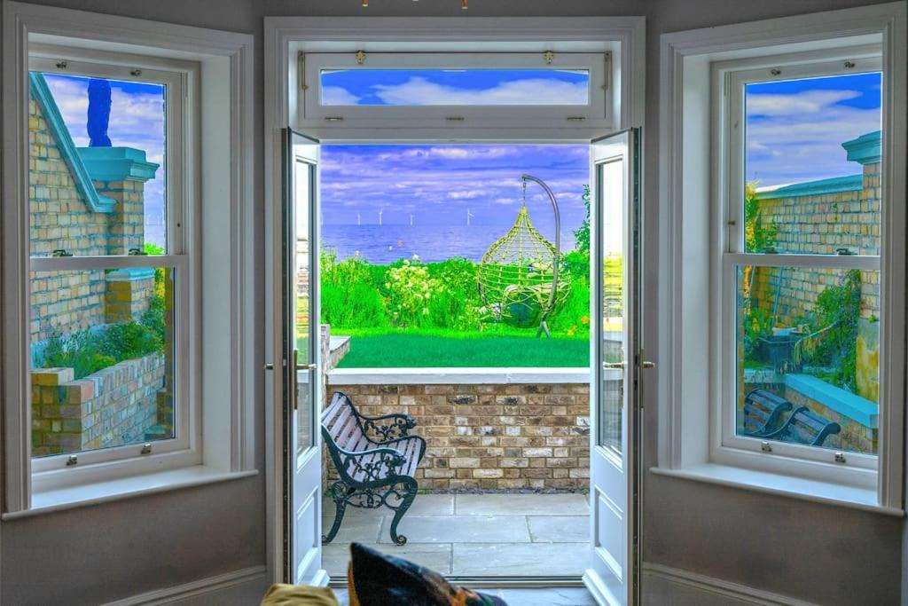 um quarto com duas janelas e uma porta com vista em Stylish Beachfront Bolthole with Stunning Sea Views and Luxury Touches em Herne Bay