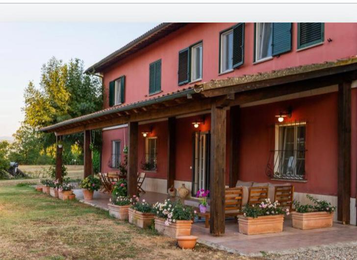 a red house with potted plants in front of it at Il Casale delle Rose in Paganico