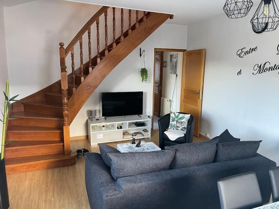 a living room with a blue couch and a staircase at Entre Lac et Montagne 4/6 personnes in Gérardmer