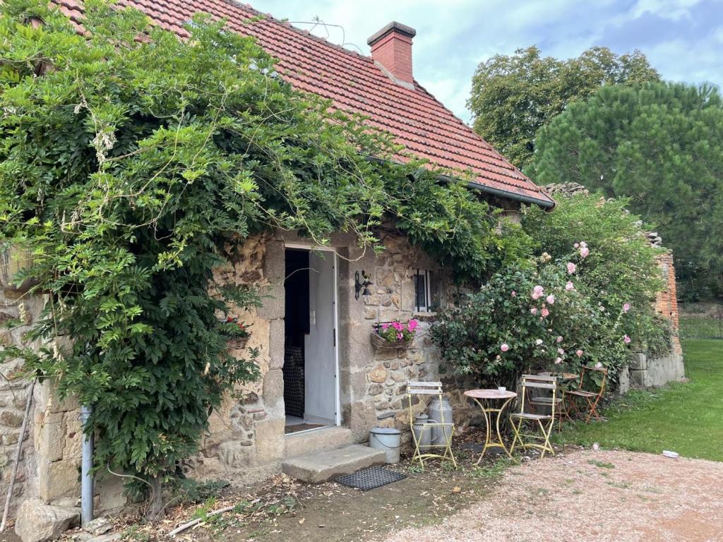 een stenen huis met een deur en stoelen en bloemen bij Gîte Terjat, 3 pièces, 4 personnes - FR-1-489-344 in Terjat