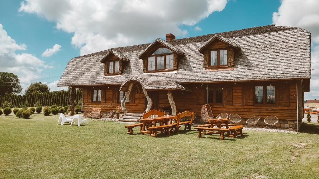 a log house with tables and chairs in front of it at Siedlisko Sodyba in Puńsk