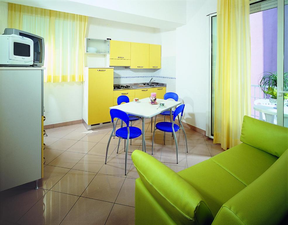 eine Küche mit einem Tisch und Stühlen sowie eine Küche mit gelben Schränken in der Unterkunft Residence Queen Mary in Cattolica