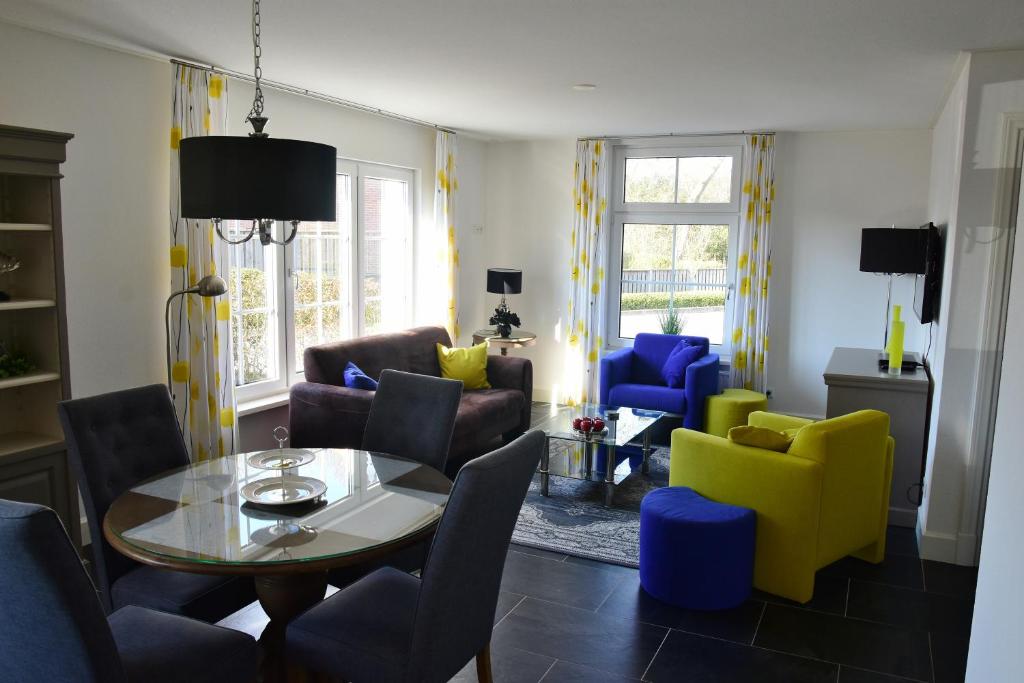 a living room with a table and colorful chairs at Woning zeldenrust 4 in Oostkapelle