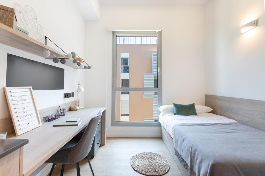 1 dormitorio con cama, escritorio y ventana en Micampus Barcelona, en Barcelona