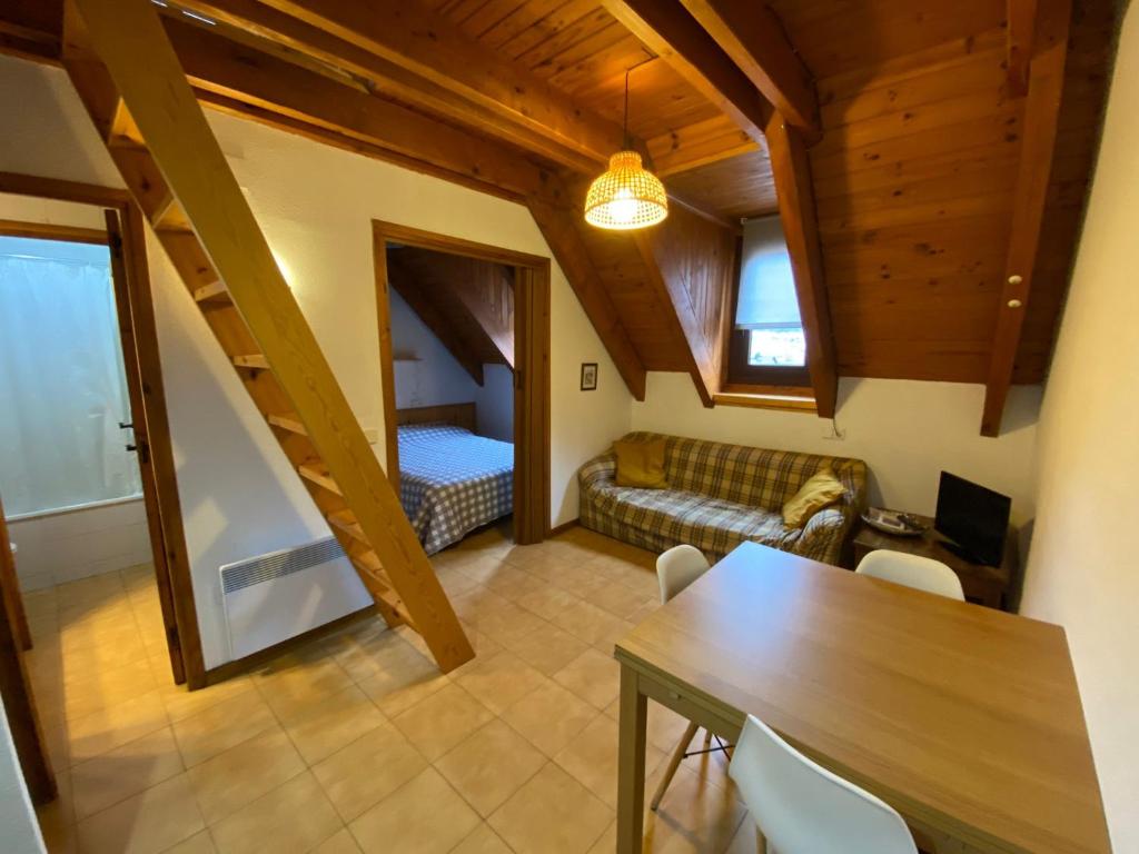 a living room with a table and a bed at Duplex Sky, muy cerca estación ski, Bonito y acogedor in Pla de l'Ermita