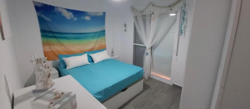 1 dormitorio con 1 cama con una pintura de arco iris en la pared en Apartamento Geminis, en La Manga del Mar Menor
