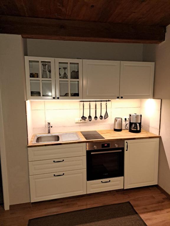 a kitchen with white cabinets and a sink at Pension Müllers Mühle in Großenhain