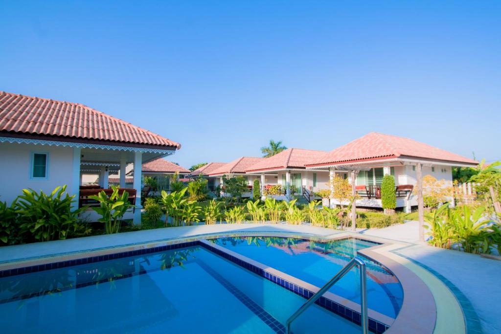 a villa with a swimming pool in front of a house at Baan Opun Garden Resort in Hua Hin