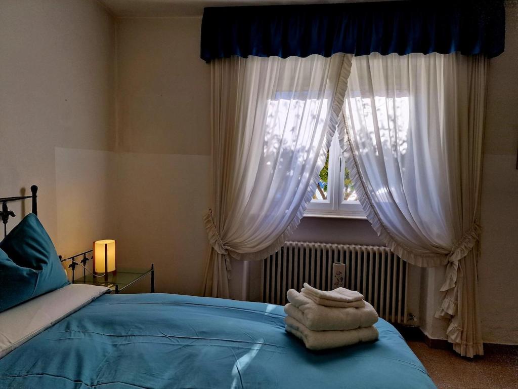 a bedroom with a bed and a window with white curtains at Casa Melina 2 in Tremezzo
