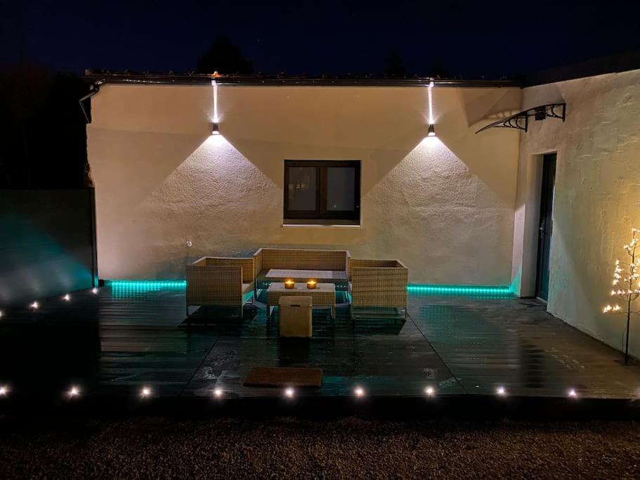 a patio with a table and chairs and lights at Makeda Love & Jacuzzi in Neuville-Saint-Amand