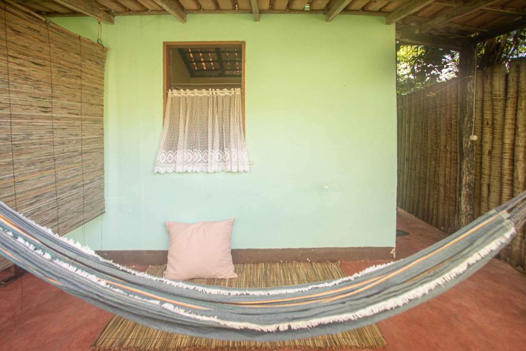 a hammock in front of a house with a window at Pousada Deus mim Deu in Caraíva