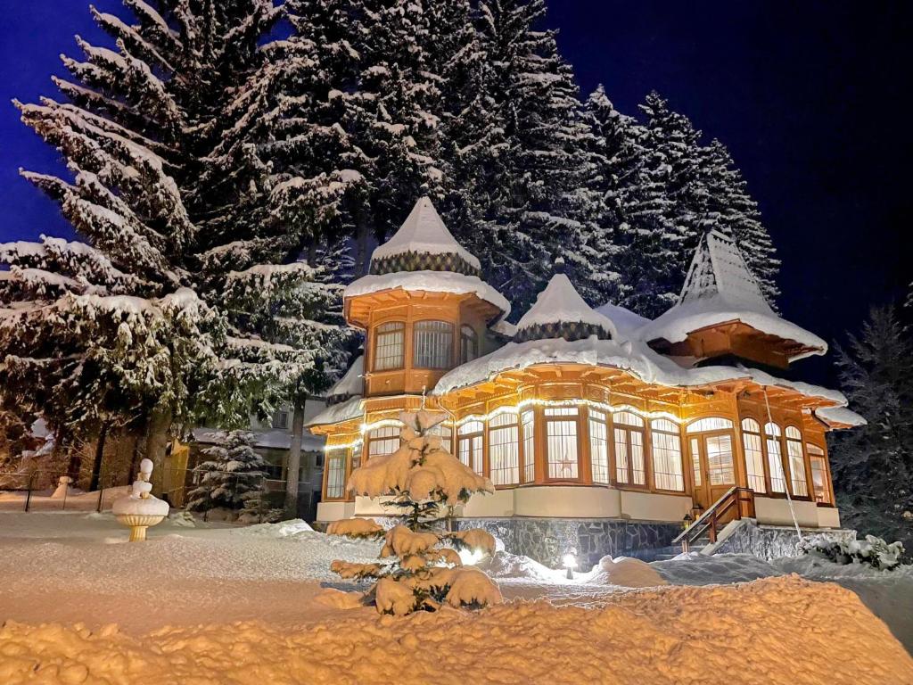 un gran edificio cubierto de nieve por la noche en Vila Sonja en Predeal