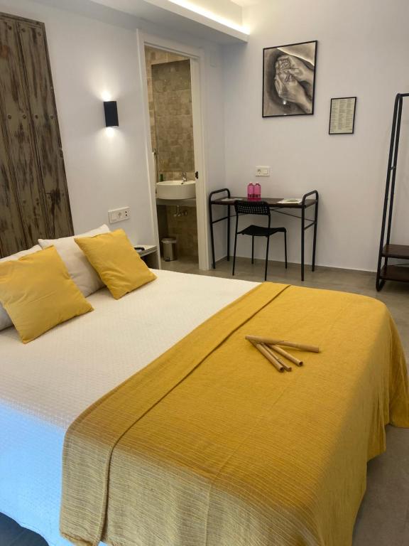 a bedroom with a large bed with yellow sheets and a table at Alojamiento El Miajon de los Castúos in Valdesalor