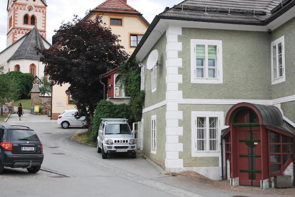 uma casa com uma porta vermelha estacionada numa rua em FEWO Gabi Haus Pacher em Sankt Peter am Kammersberg
