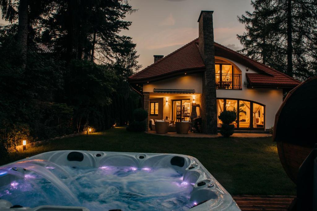 a hot tub in front of a house at night at Zarabie Residence in Myślenice