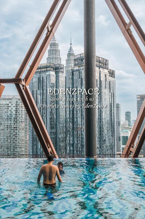a man in a infinity pool on the top of a skyscraper at Scarletz Suites by Edenzpace @ KLCC Area in Kuala Lumpur