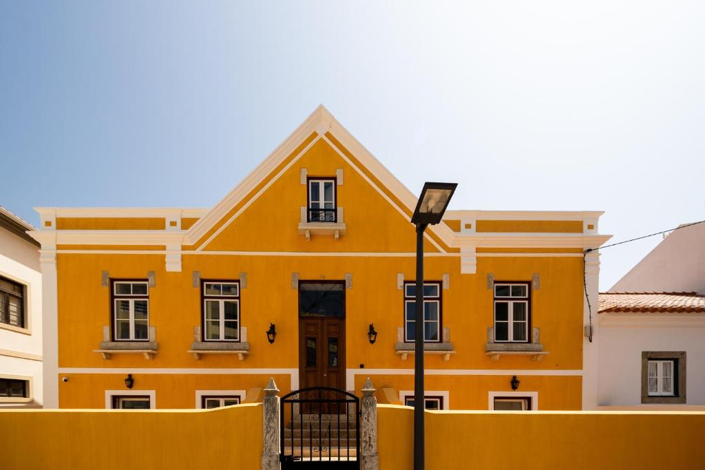 um edifício amarelo com uma luz de rua em frente em Villa Galega em Silveira