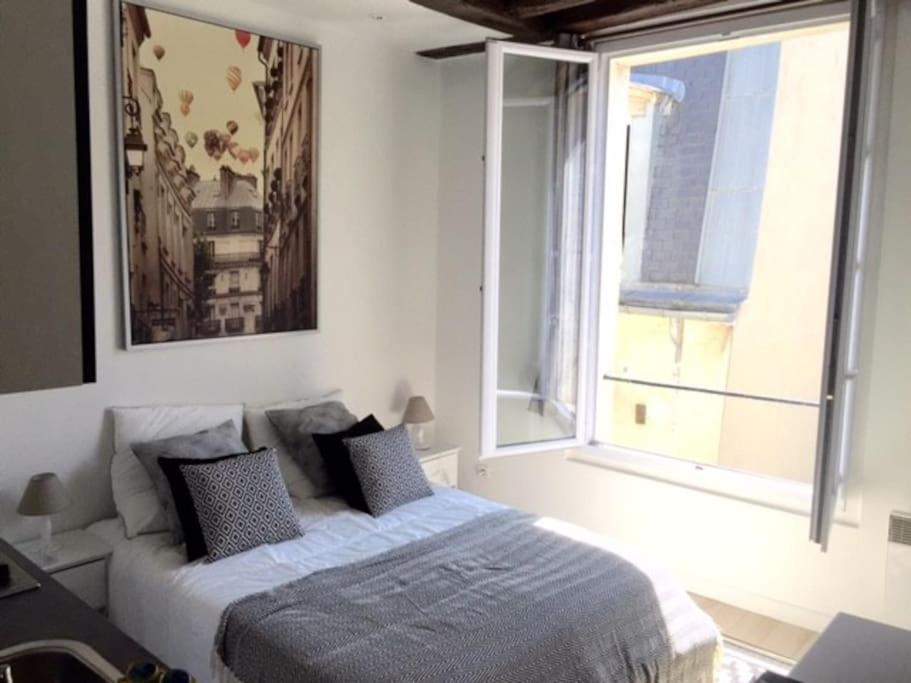 une chambre avec un lit et une grande fenêtre dans l'établissement So cute typical french apartment (46), à Paris