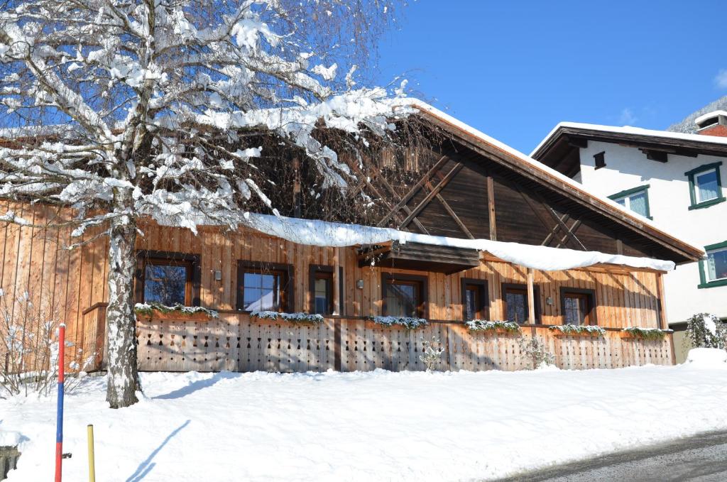 ein schneebedecktes Haus mit einem Zaun in der Unterkunft Pension zum Schreiner in Hermagor