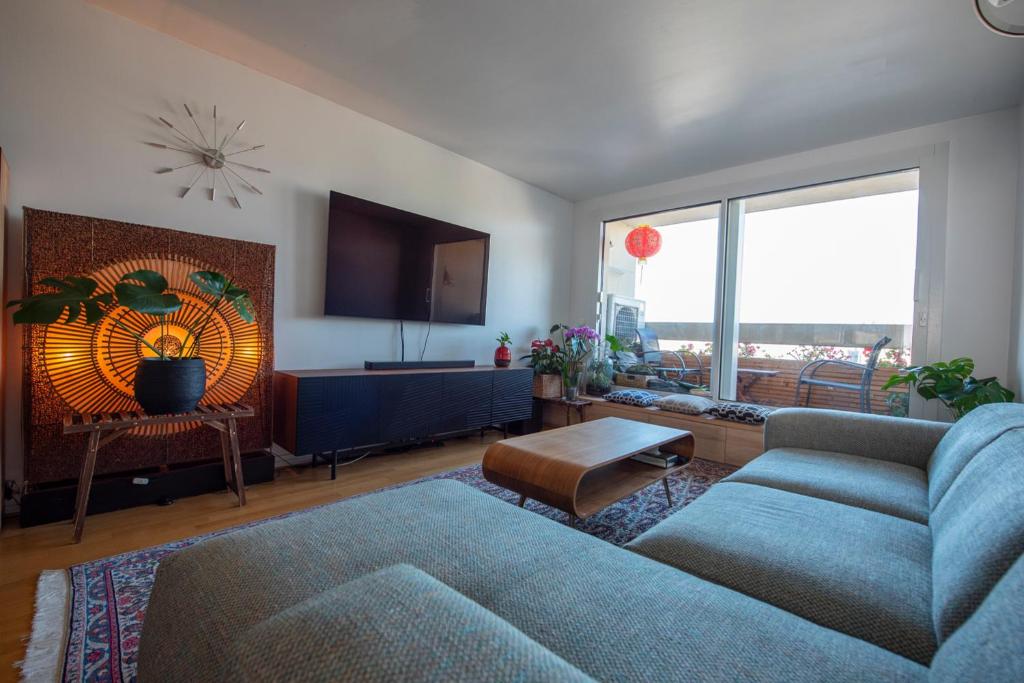 un salon avec un canapé bleu et une grande fenêtre dans l'établissement Attica, à Paris