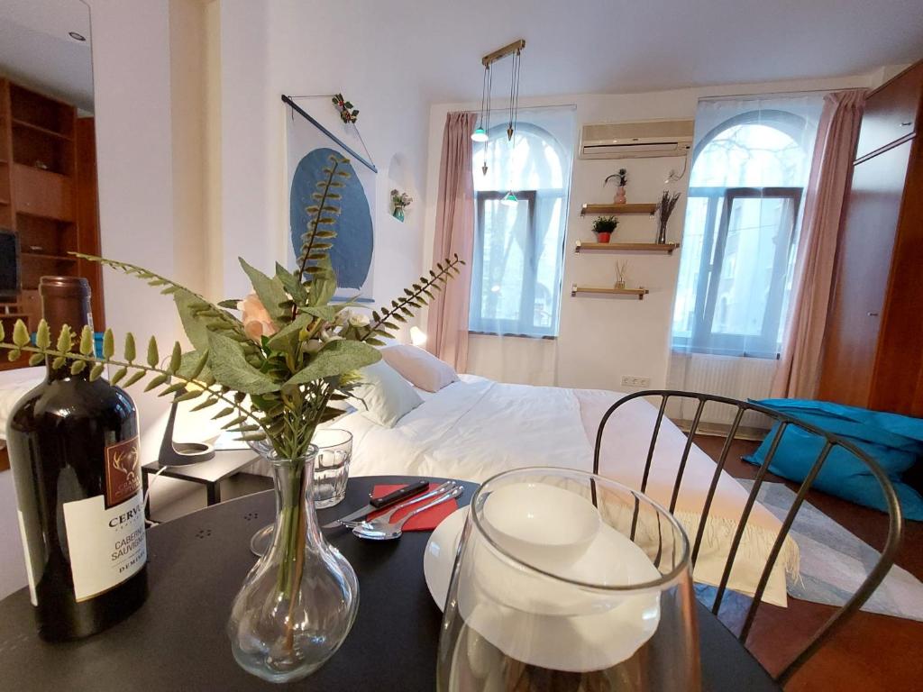 a table with a bottle of wine and a vase with flowers at Sweet Dreams Suites Cosy Studio Piata Romana in Bucharest