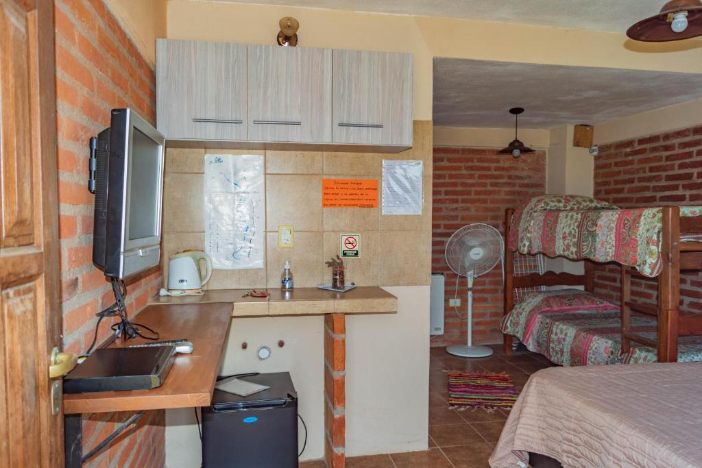 a bedroom with a bed and a desk with a television at Posada Tinktinkie in Santa Rosa de Calamuchita